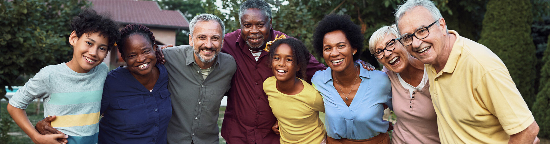 Mixed age kids and adults hug in a group.