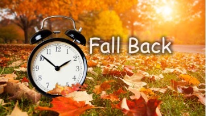 Fall Back. An alarm clock sits on a lawn covered in fallen leaves