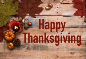 Happy Thanksgiving. Pumpkins and leaves scattered on a wooden table.